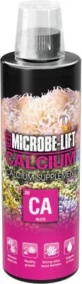Bouteille de supplément calcium pour aquarium récifal, coraux colorés en arrière-plan.